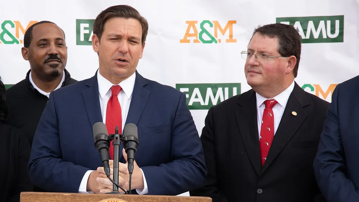 Two men in suits stand behind a podium with the Florida state seal on it.