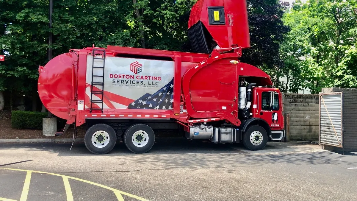 Red garbage truck in parking lot with Boston Carting Services logo