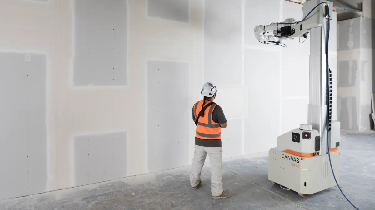 A worker uses a robot to install and finish drywall at a jobsite.