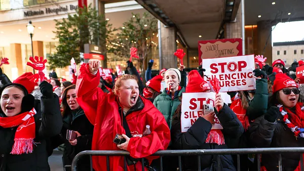 Nurses chant and hold signs saying "Stop silencing nurses" outside of a New York City hospital building.