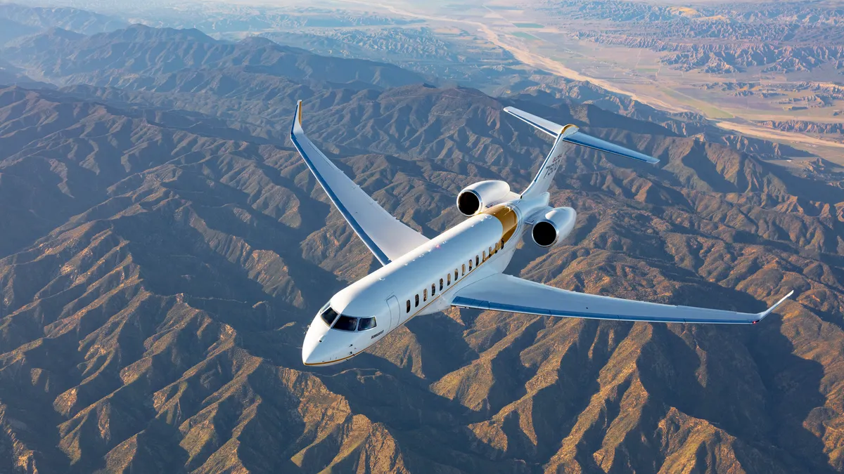 Global 7500 Bombardier aircraft flying in the blue sky with land beneath it.