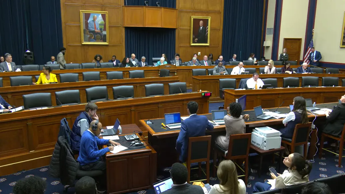 A wide shot of a hearing of the House Committee on Education and the Workforce. Multiple rows of seats with lawmakers.