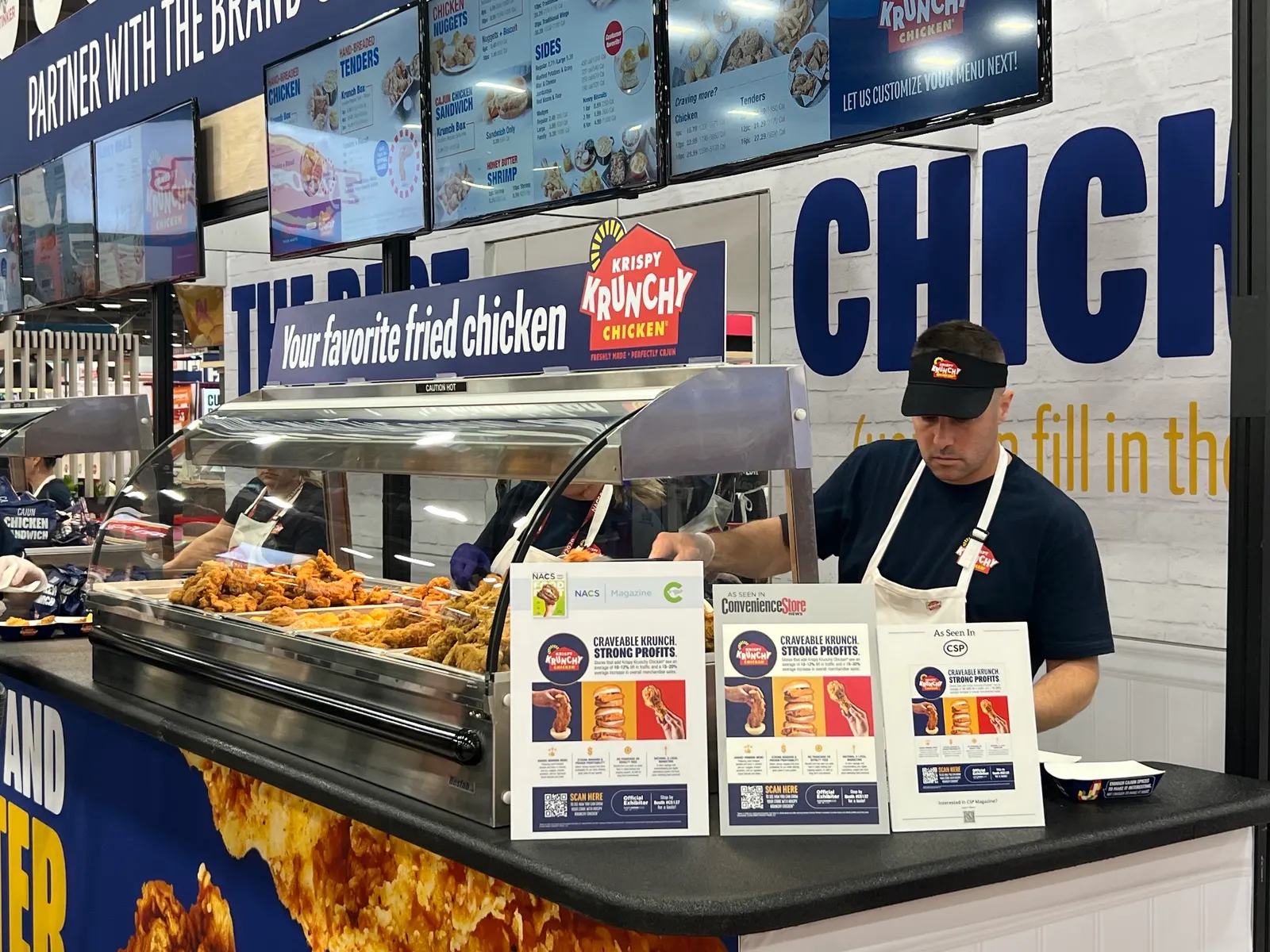 A worker serves up fried chicken at the Krispy Krunchy Chicken booth at the 2026 NACS Show