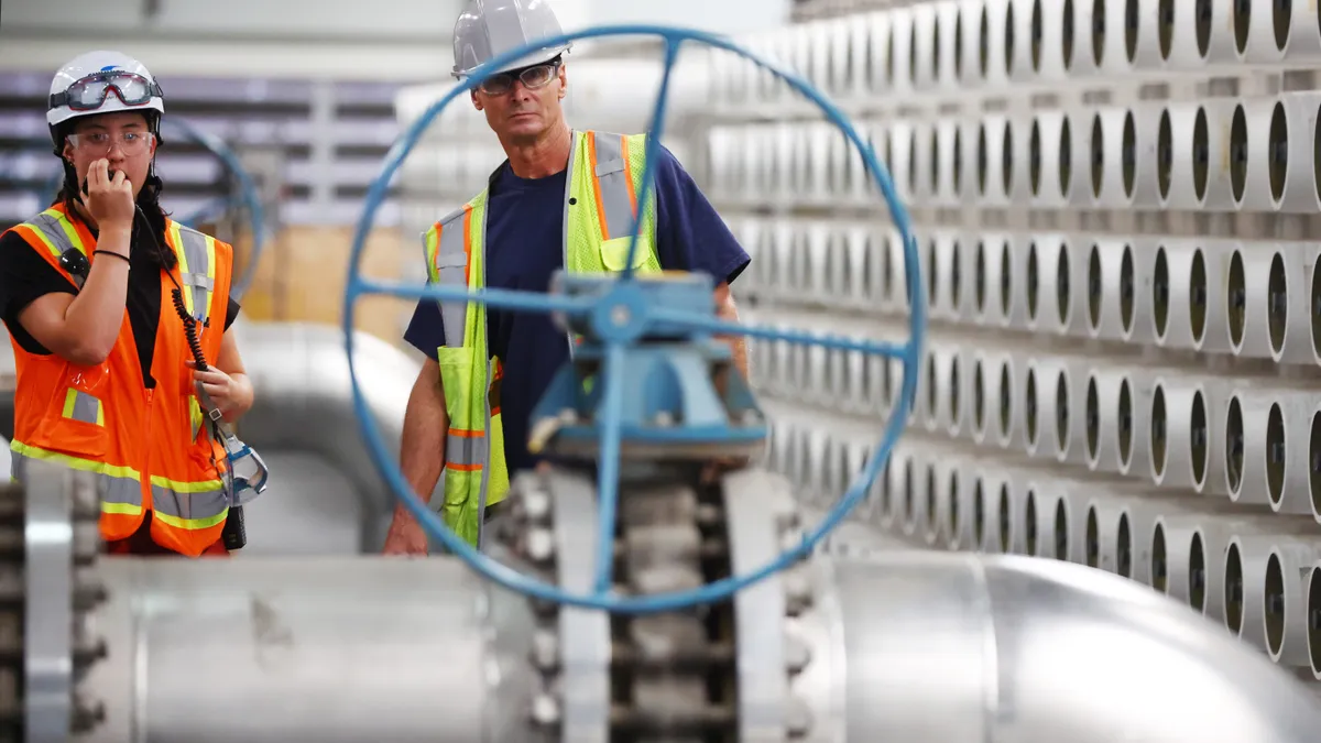 Two workers inspect equipment at a wastewater plant.