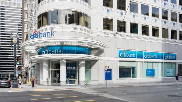 The building features a modern glass façade with the Citibank logo prominently displayed above the entrance. Pedestrians are visible on the sidewalk, and the surrounding area includes other commercial buildings.