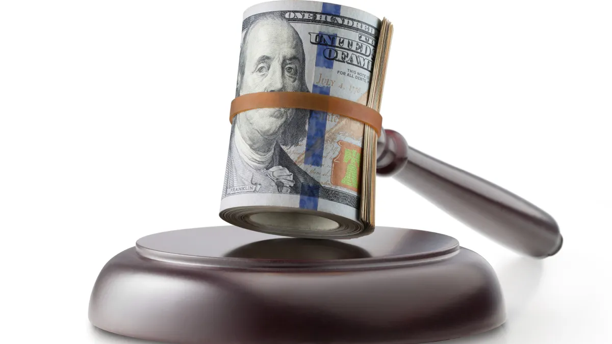 Judge gavel with roll of dollar banknotes on white background.