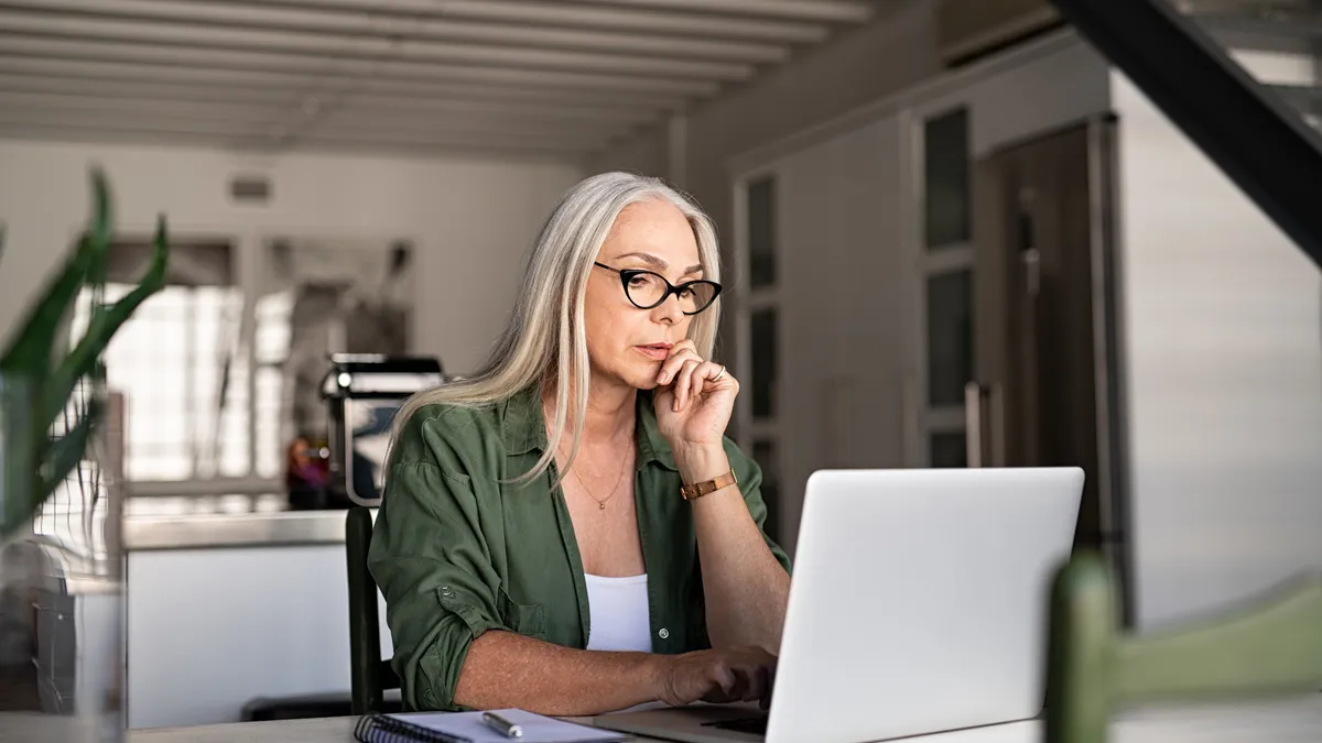 Focused woman with white hair at home using laptop