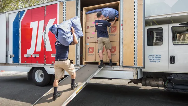 JK Moving Services workers carrying wrapped items.