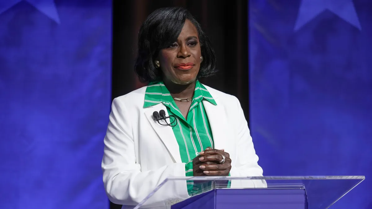 Woman in white suit standing at debate lectern