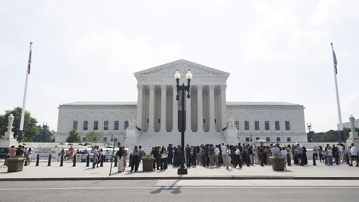 The U.S. Supreme Court Building front side is pictured with a crowd a people in front of the building.
