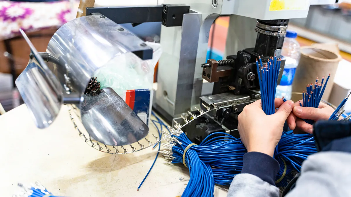 An employee working with machine parts checks industrial equipment cables.