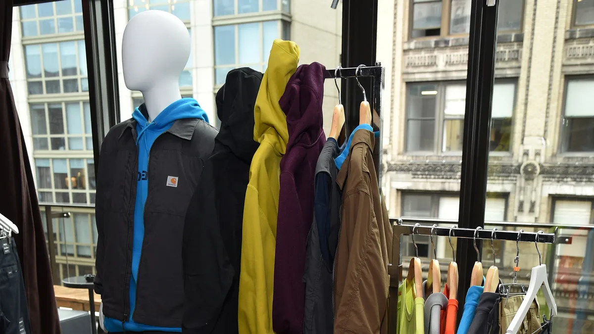 An in-store display of Carhartt items is pictured, including multiple clothing racks, a mannequin and a sign.