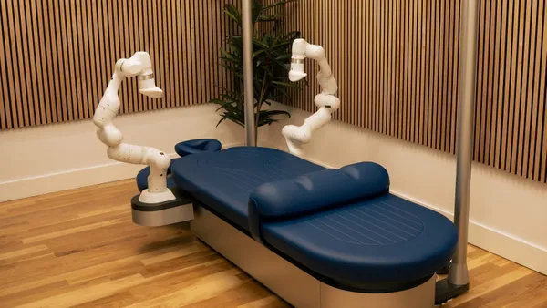 Robotic massage arms beside a blue massage table.