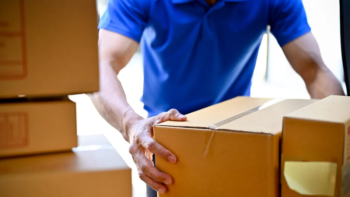 A person in a blue shirt holding a package.