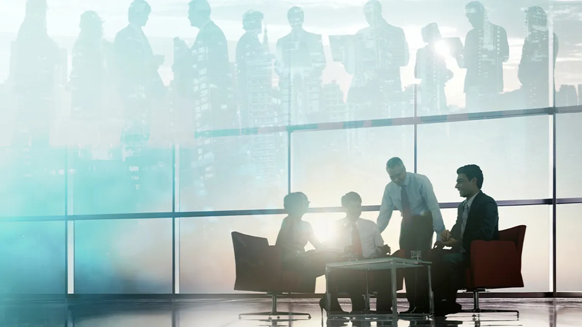 Four business professionals are seated around a table in a modern office setting. Overlay of standing figures and a cityscape evokes a collaborative atmosphere.
