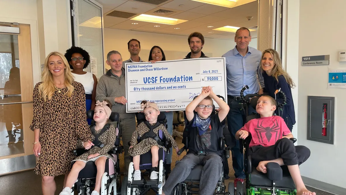 A group of researchers and patients from a research lab at UC San Francisco pose with a large check.
