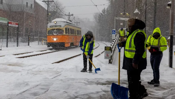Workers clear snow from the tracks and station on January 25, 2026 in Milton, Massachusetts.