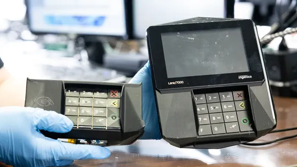 Gloved hand holds card reader device and illegal skimmer next to it.