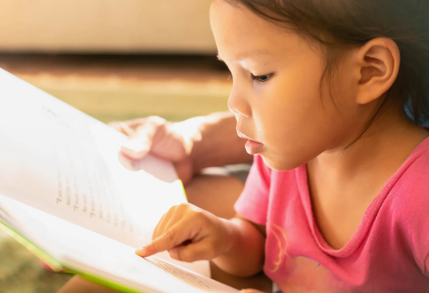 A young student points to pages in a book.