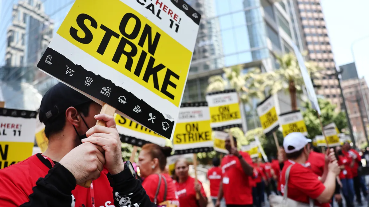 Workers in red T-shirts hold picket signs.