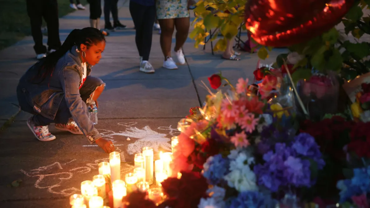 A woman chalks a message at a makeshift memorial outside of Tops market on May 15, 2022 in Buffalo, New York.