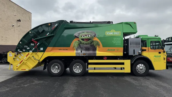 Side view of a garbage truck with a photo of Oscar the Grouch