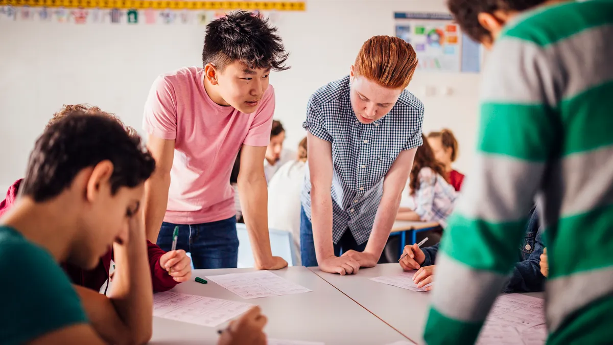 A multicultural group of teen boys works around a table on a school project.