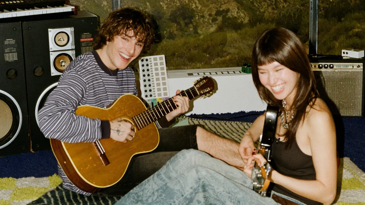 Two people sitting on the floor playing guitar