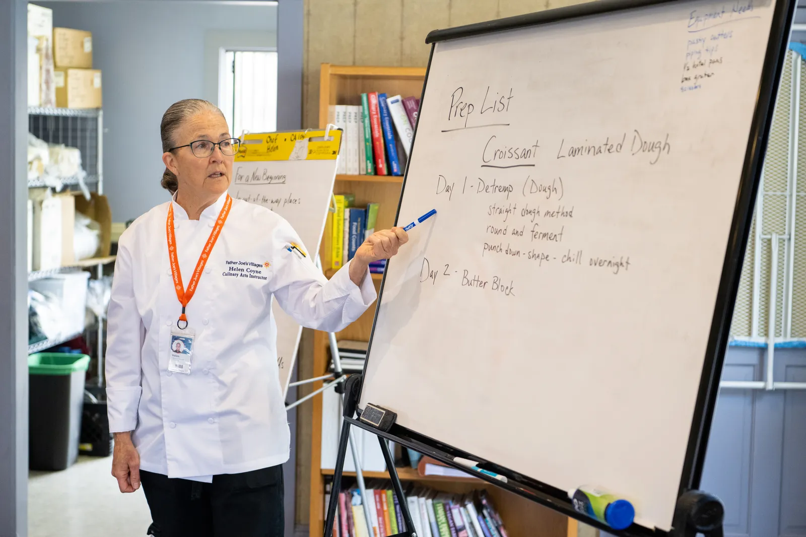 A cooking instructor points to a whiteboard during a lesson about making croissants.