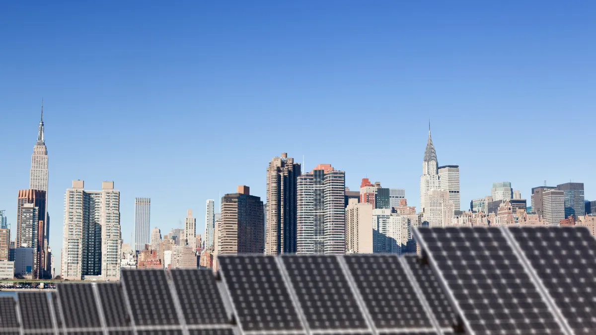 Solar panels on a rooftop with New York CIty's skyline in the background.