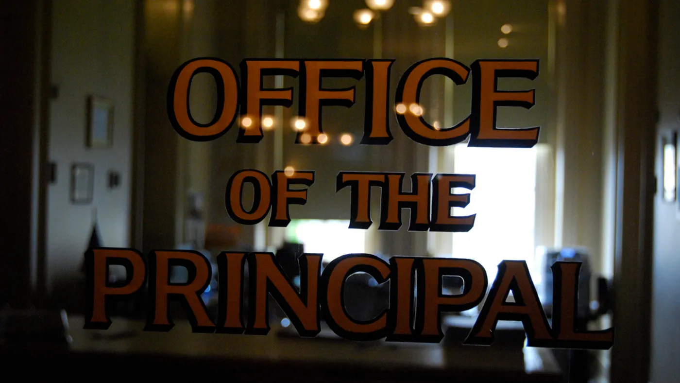 The door to a principal's office is shown. "Office of the Principal" is painted on the door's window.