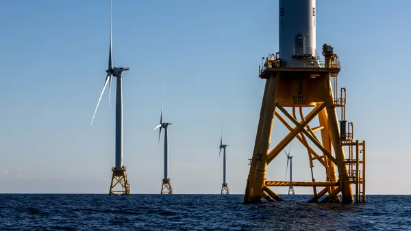 Offshore wind farm turbines spin over the ocean.
