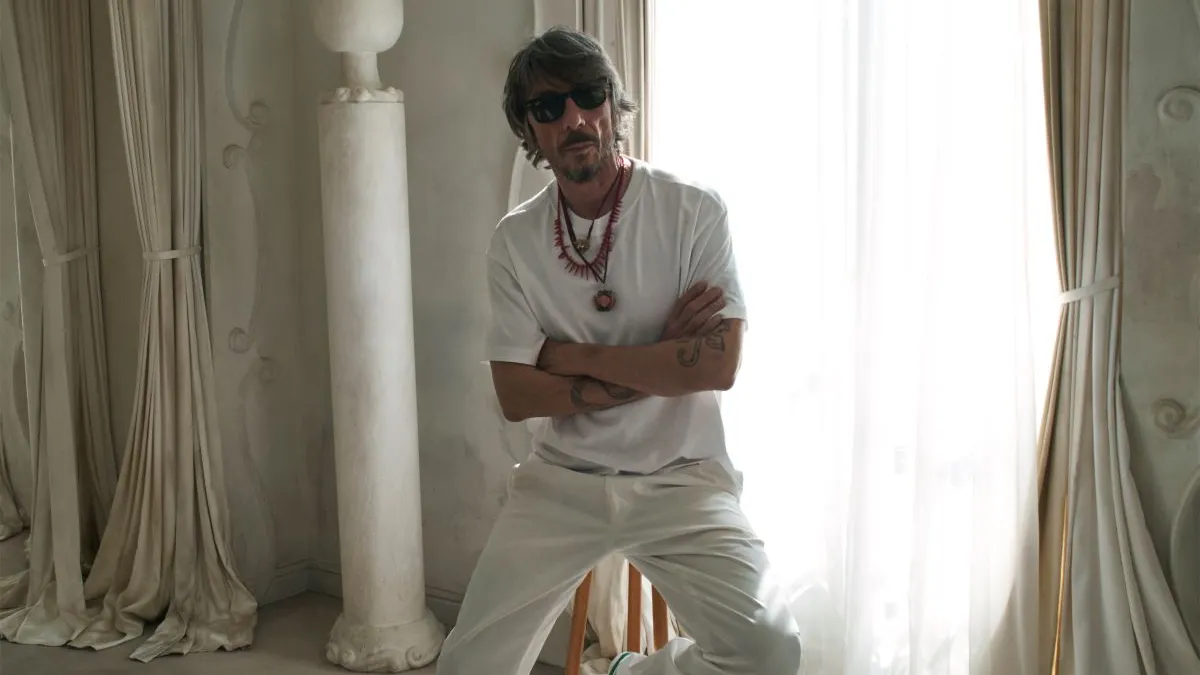 Pierpaolo Piccioli is seated in a room with window lighting on a stool.