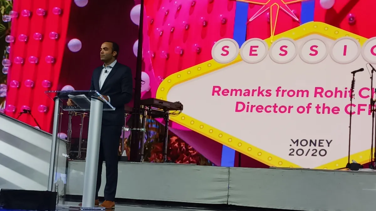 Consumer Financial Protection Bureau Director Rohit Chopra standing at a podium on stage.