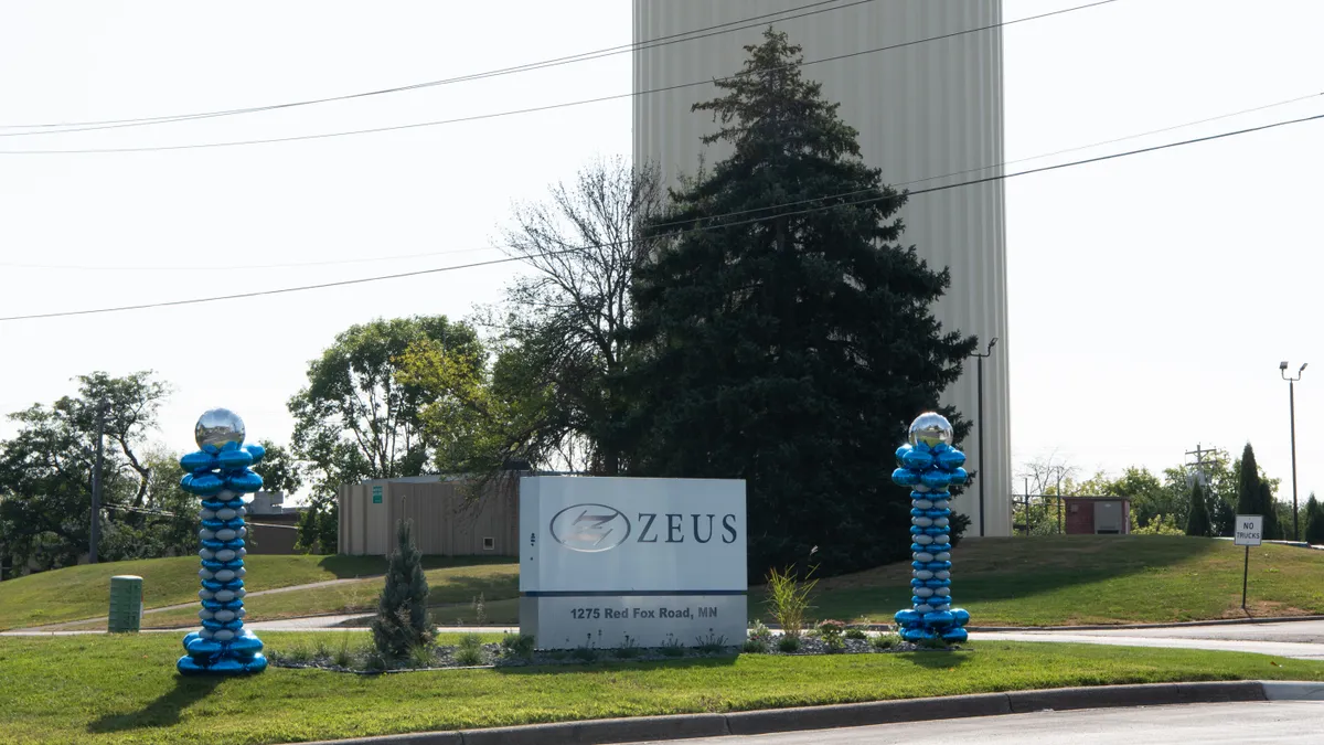 A sign saying "Zeus" is is in front of a tower that says "Arden Hills"