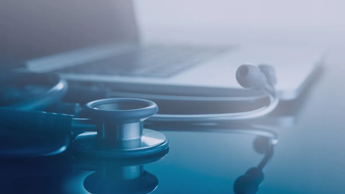 Medical technology background, close of doctor's stethoscope and laptop computer on office desk with reflection, black and white.