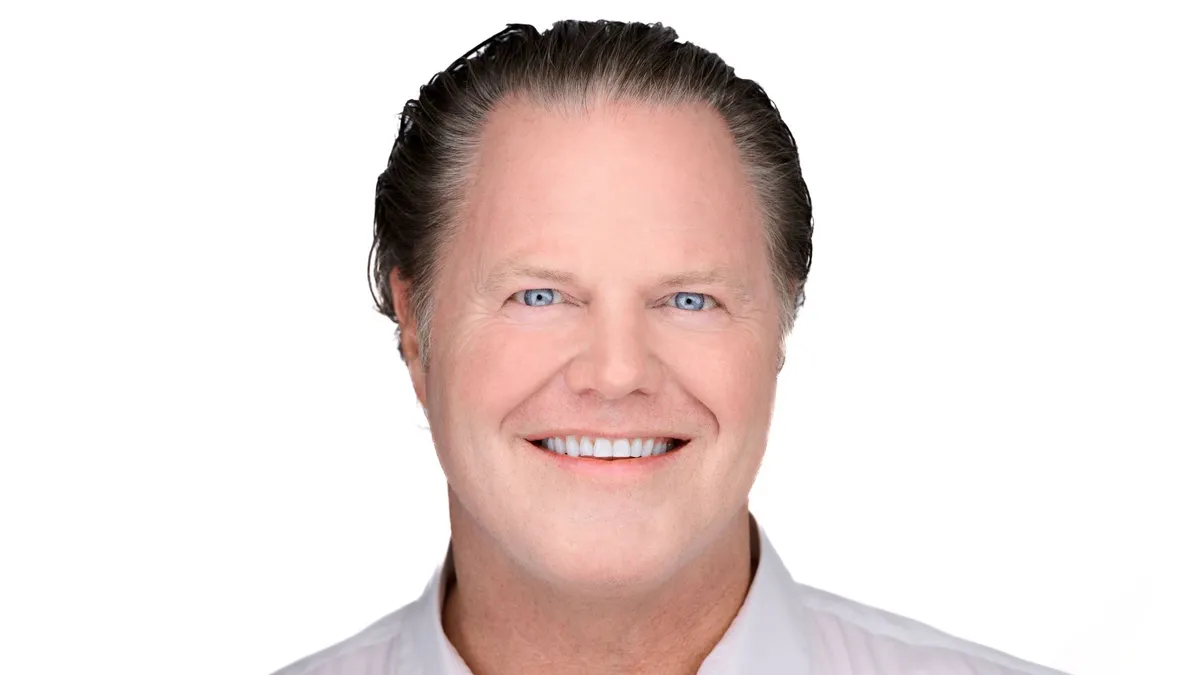 A portrait of a smiling person dressed in business attire on a white background.