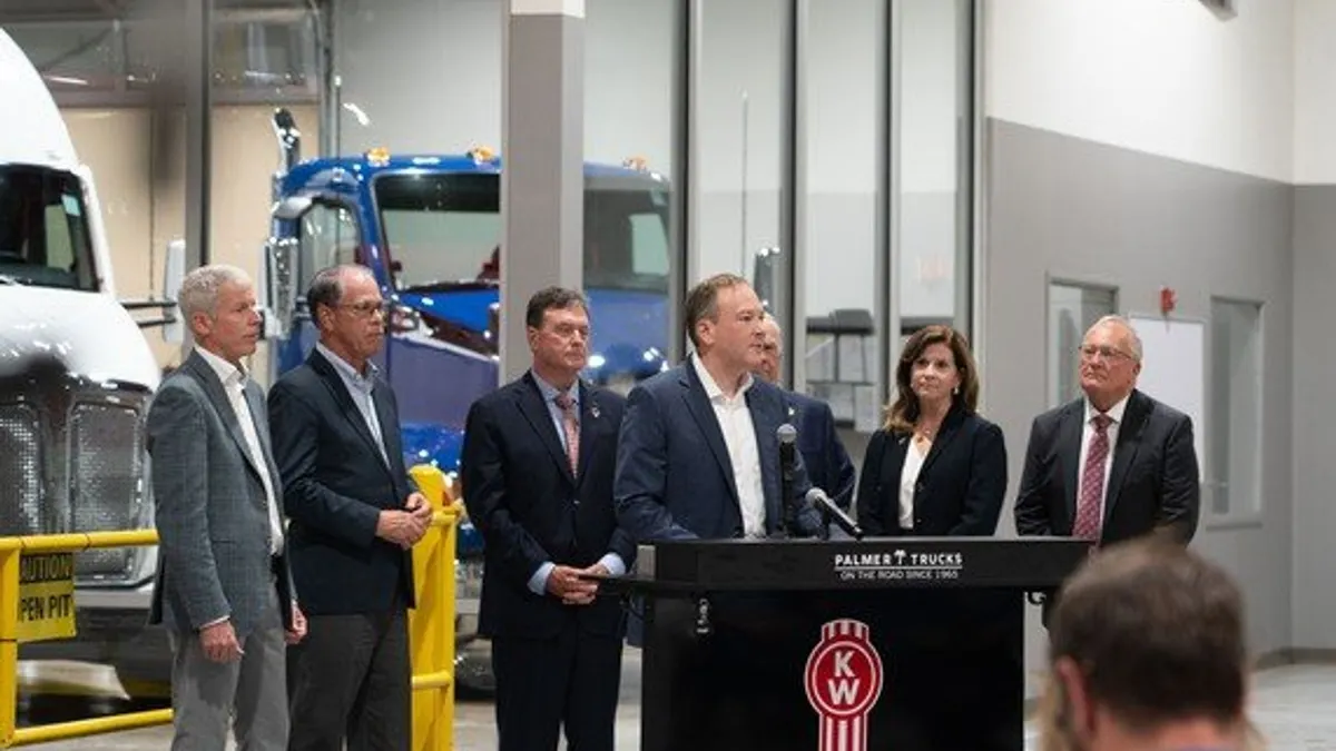 Officials gather at a dealership in Indiana around a podium.
