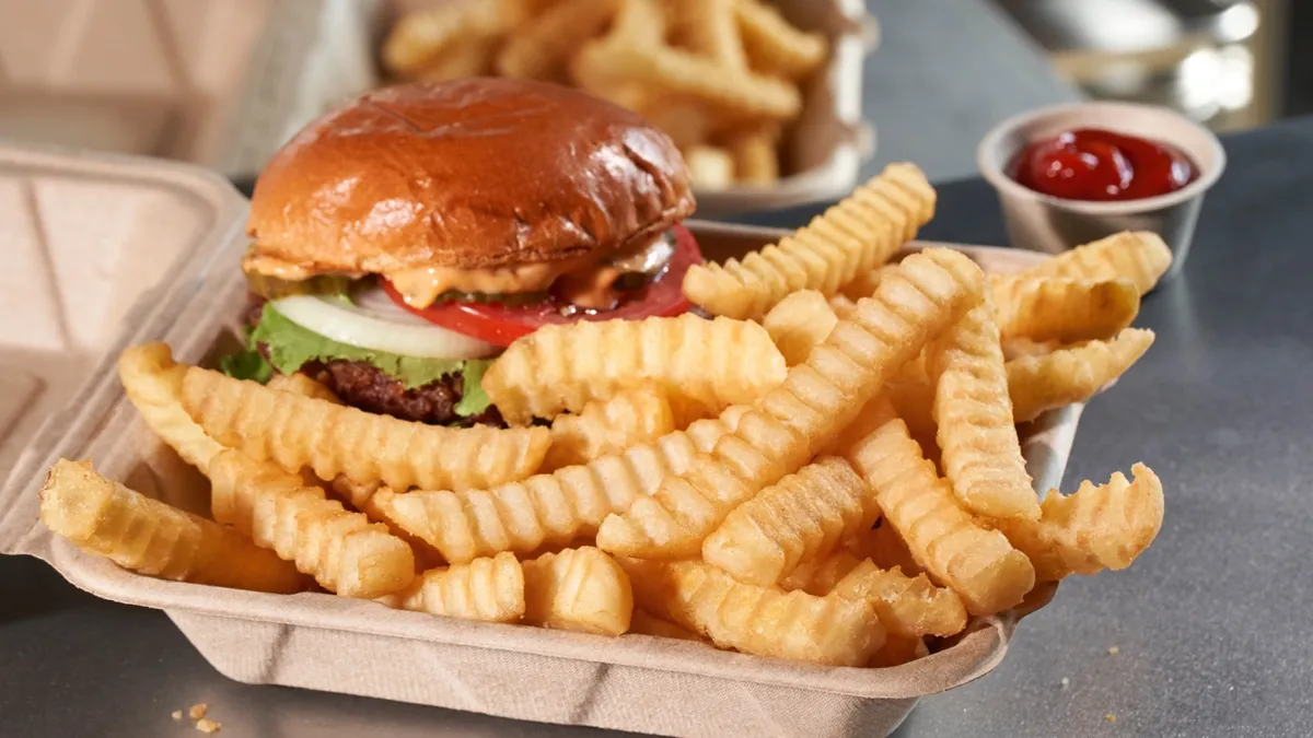 Fries and a burger sit in a to-go container.