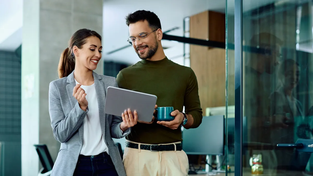 Two colleagues talking and looking at a tablet