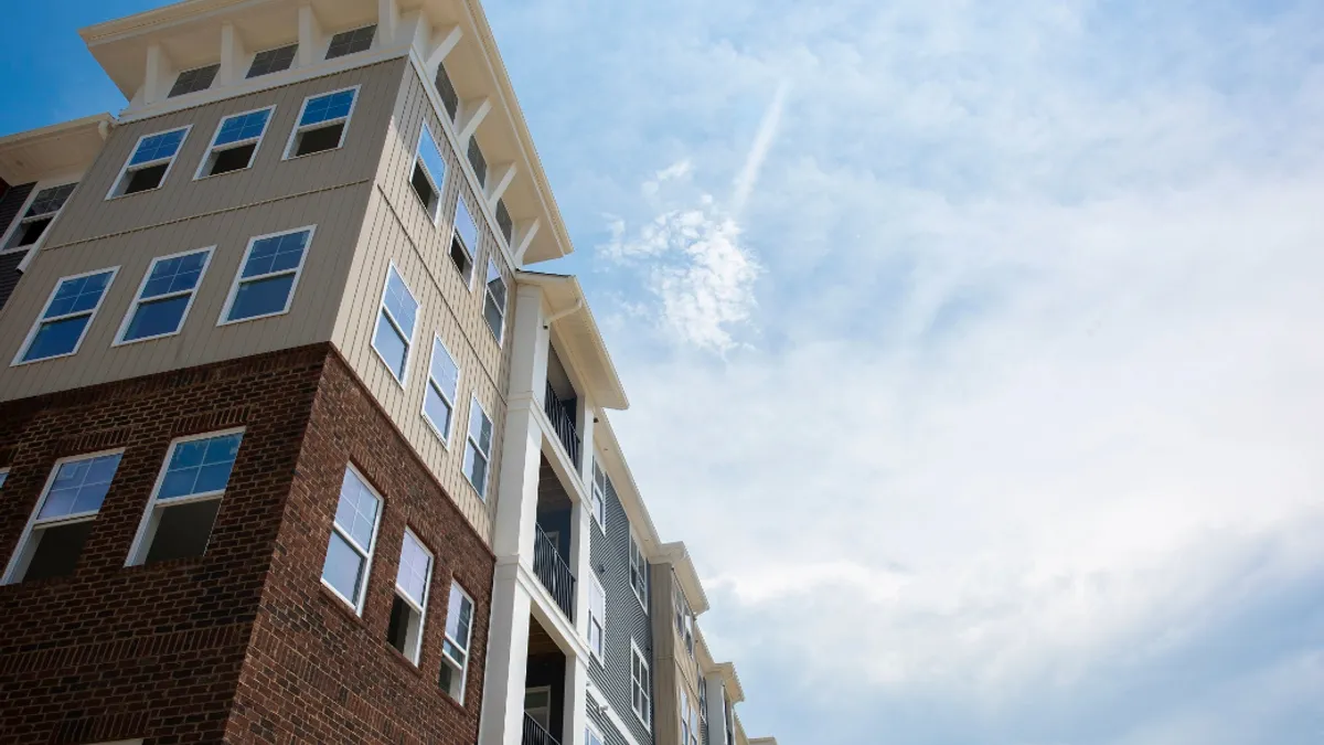 A low angle shot of a multistory apartment with the blue partly cloudy sky in the background.