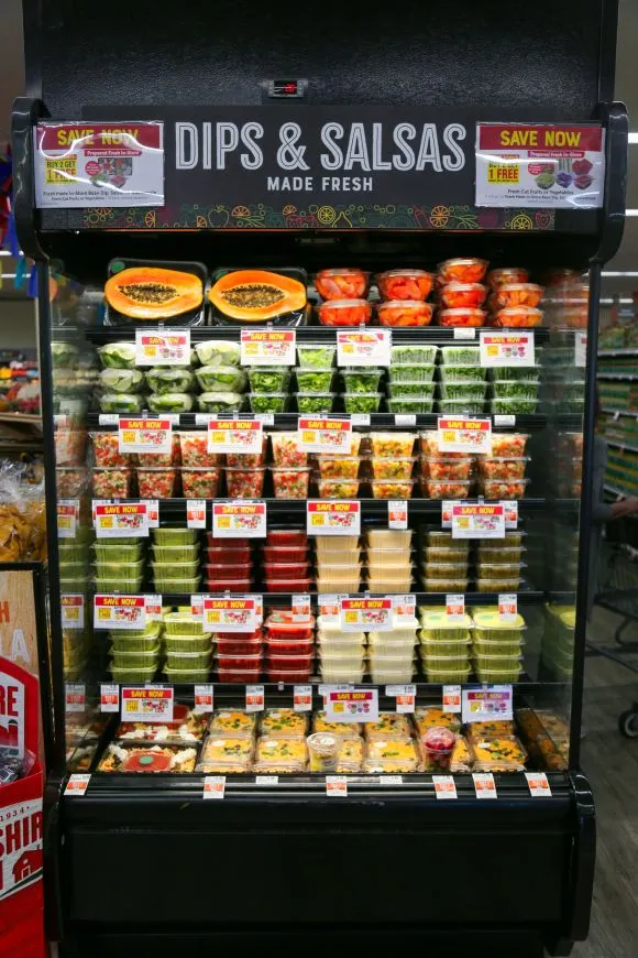 Dips and salsa on sale in a refrigerated end cap display in a grocery store