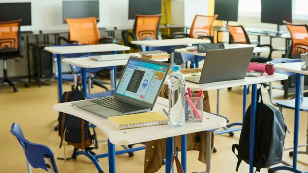 A school classroom with laptops open on student desks.