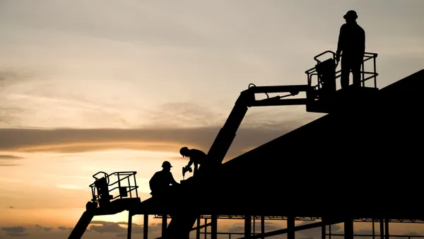 A group of construction workers at a jobsite at sunrise.