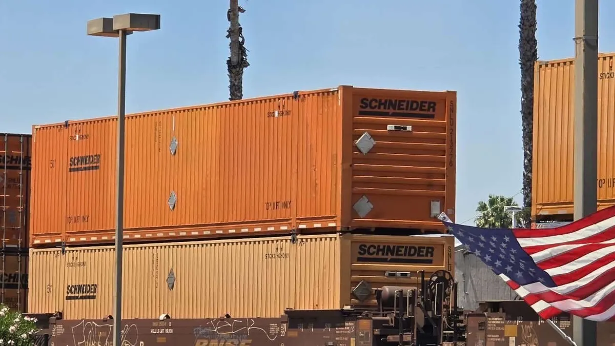 Schneider National orange containers onboard a rail train.