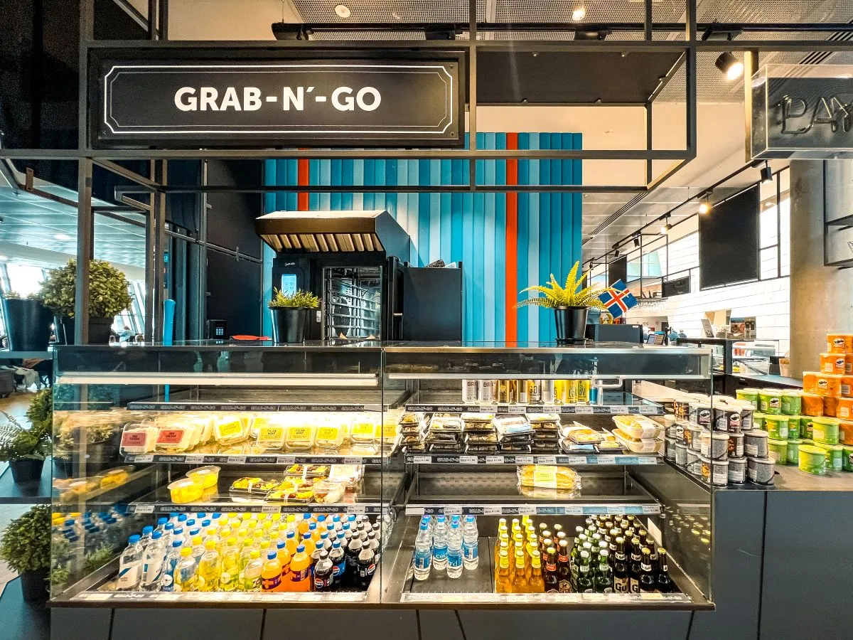 A bakery case with various sandwiches and drinks within an airport for grab and go.