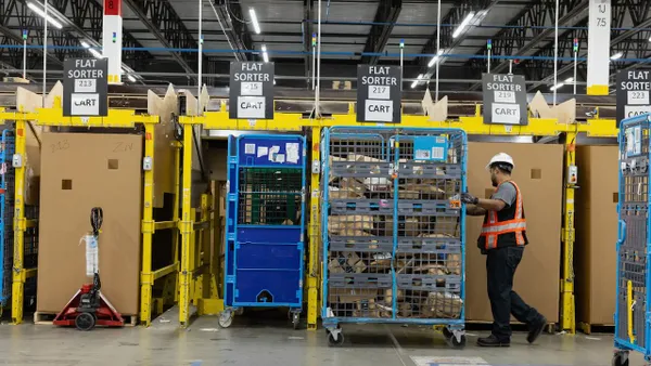 A warehouse worker pushes a large cart of packages.