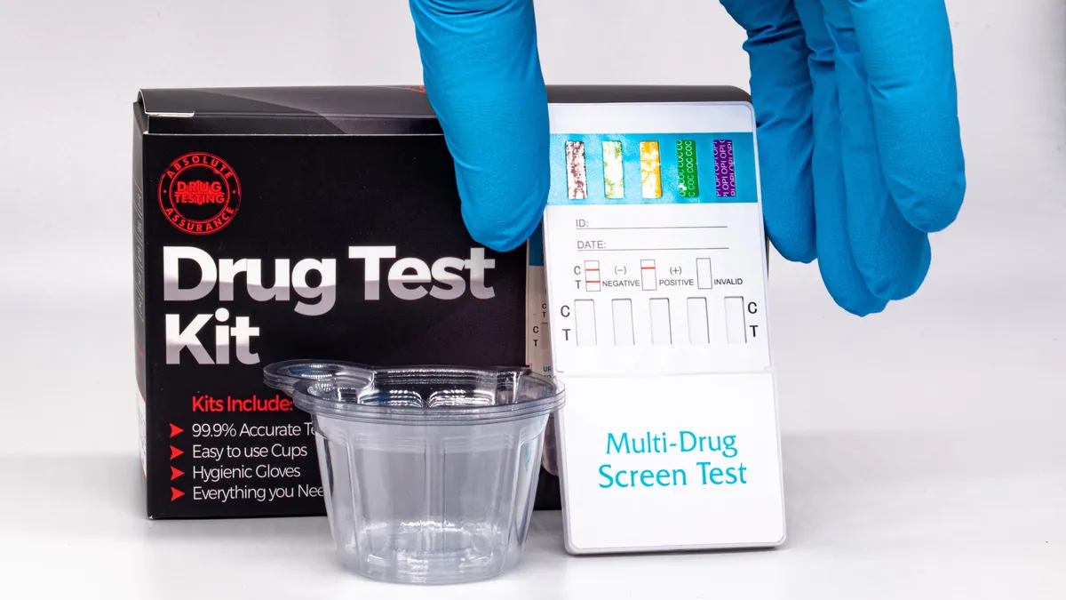 A gloved hand holds a drug testing kit