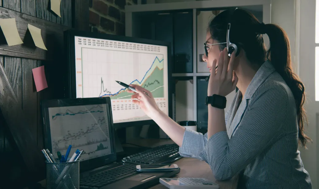 person at desk with graphs on monitors