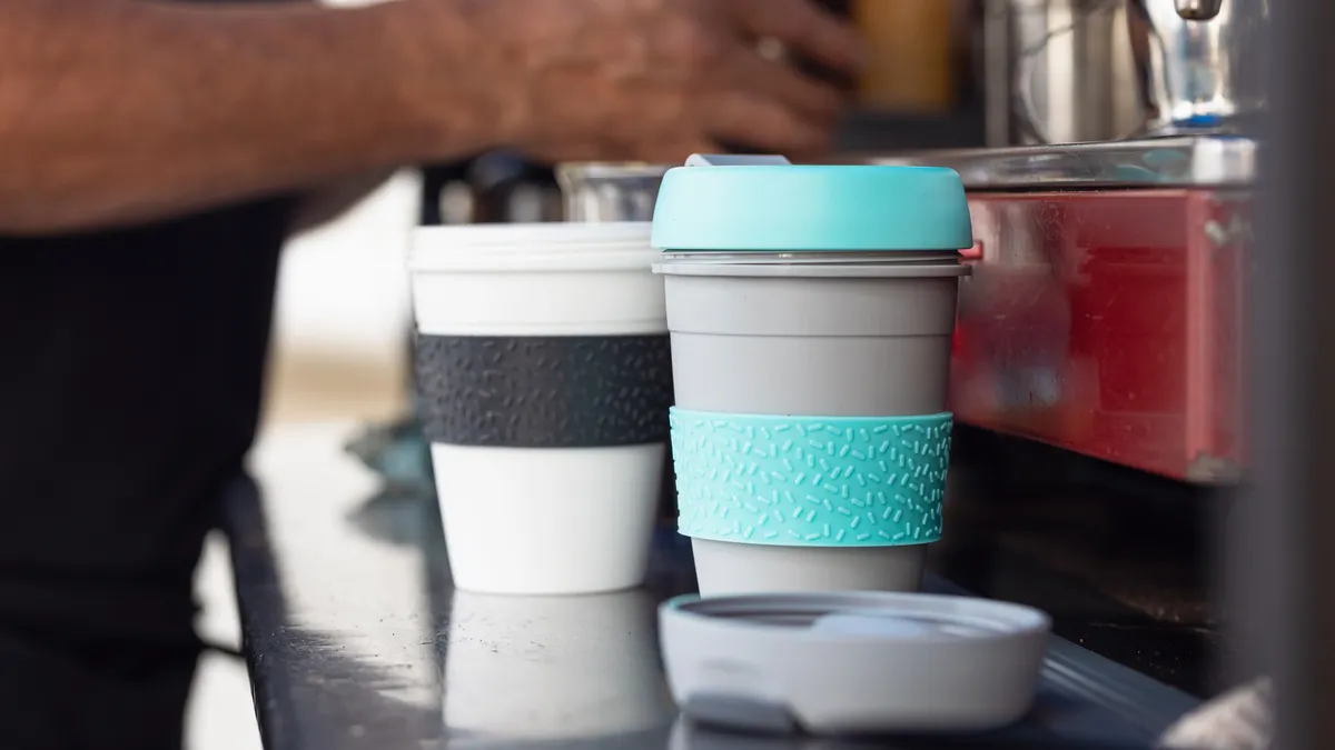 Two reusable coffee cups at a coffee shop